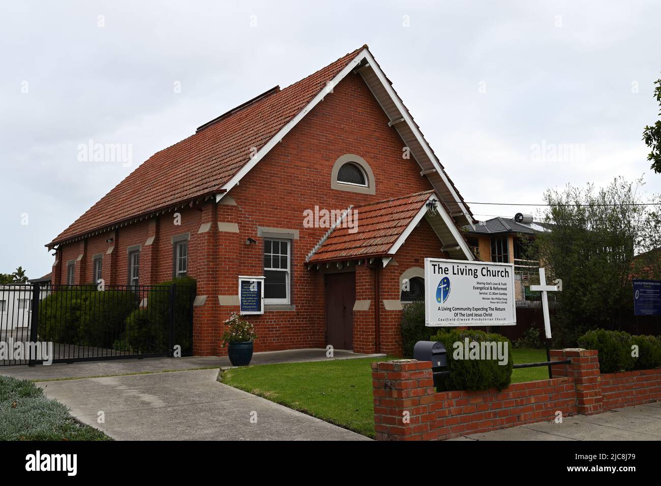 The Living Church, or Caulfield-Elwood Presbyterian Church, a red brick and tile structure behind Neerim Rd facing signage, in suburban Melbourne Stock Photo
