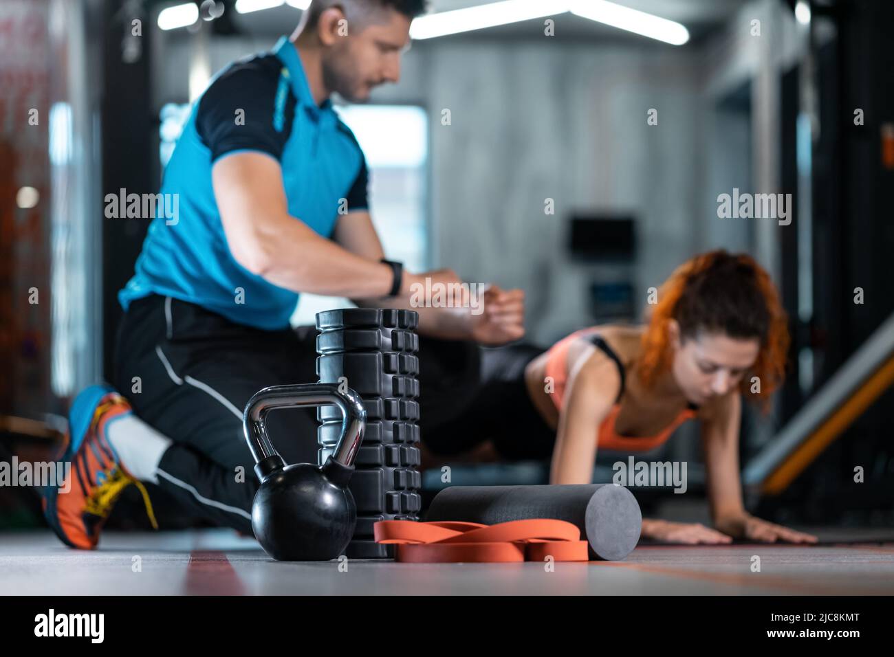 fitness female exercising plank with personal trainer with equipment in gym Stock Photo