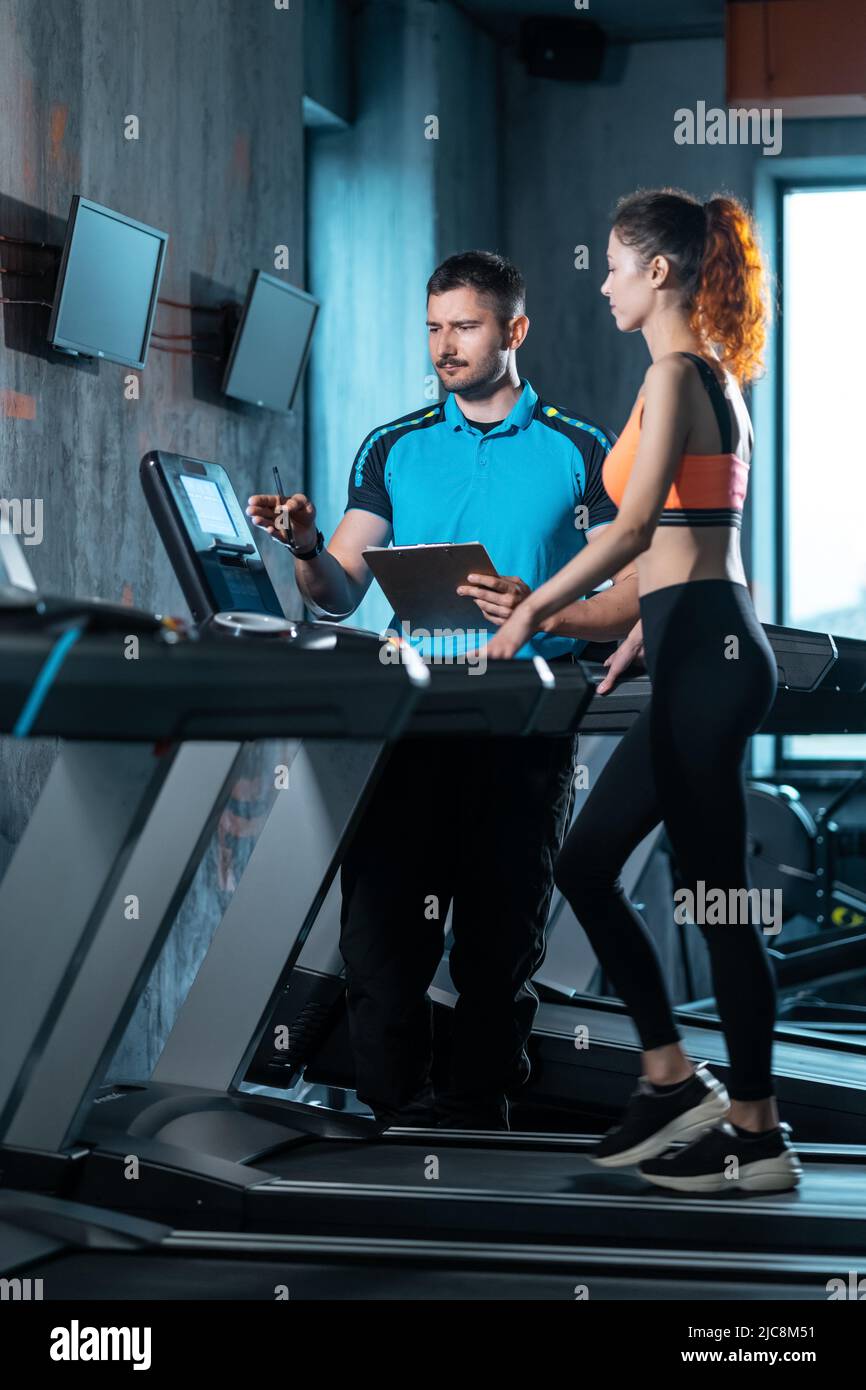 young beautiful woman has workout on treadmill with personal trainer and running Stock Photo