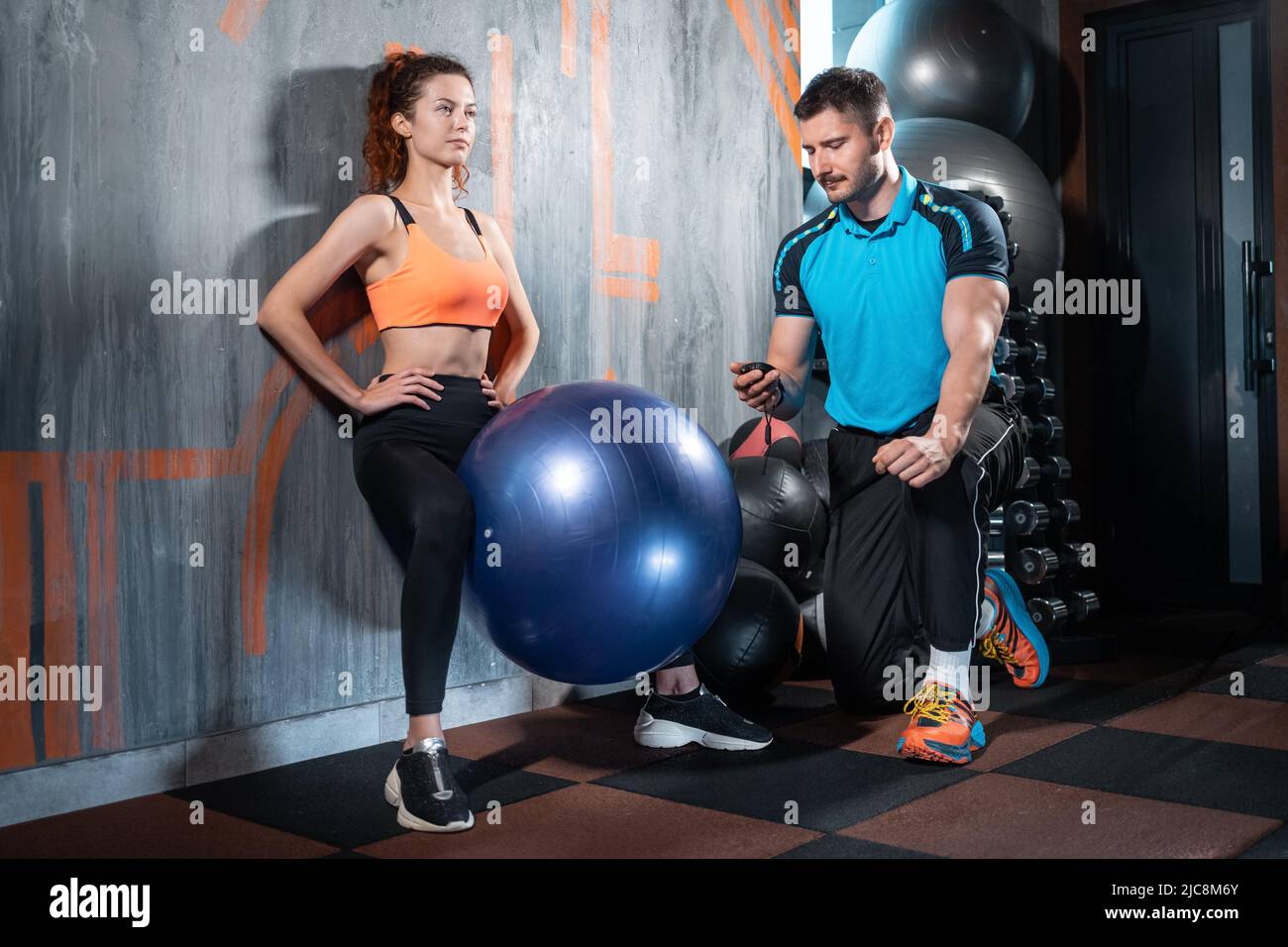 young female has workout and exercising with fit ball and personal trainer gym Stock Photo