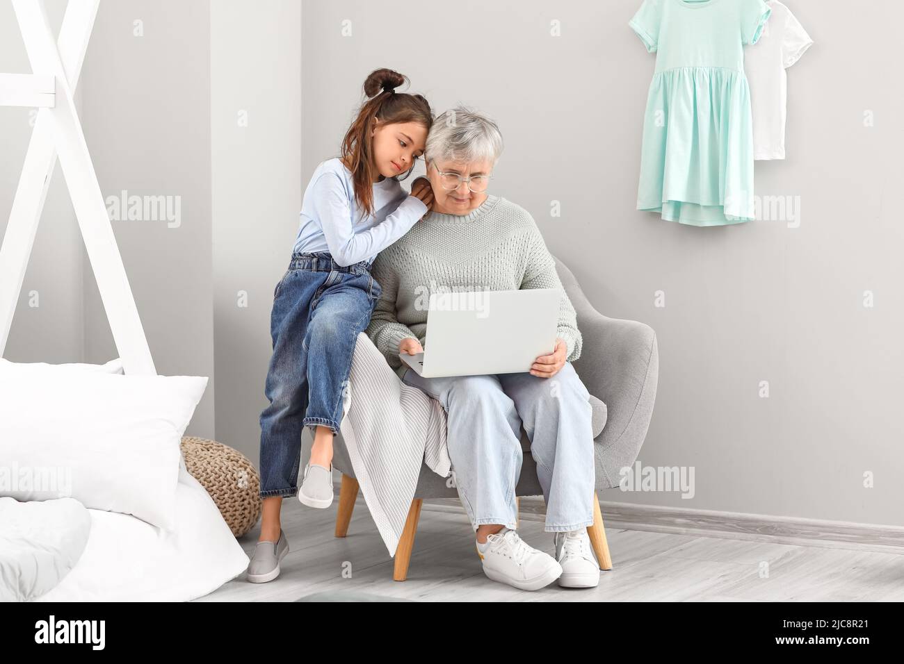 Little girl and her grandma using laptop in bedroom Stock Photo - Alamy