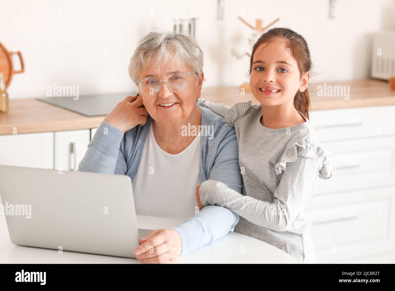 Little girl with her grandma using laptop in kitchen Stock Photo - Alamy