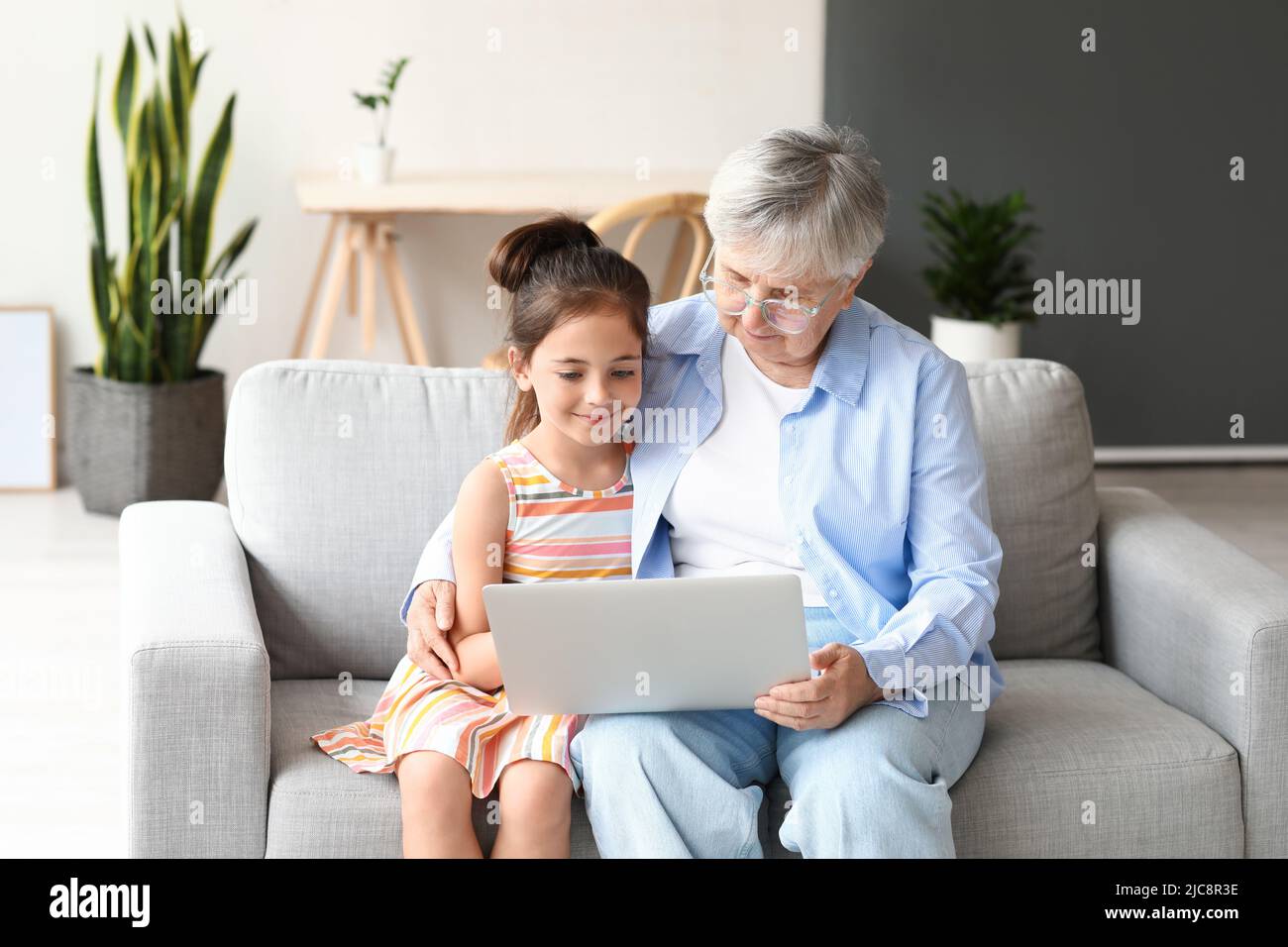 Little girl with her grandma using laptop at home Stock Photo - Alamy