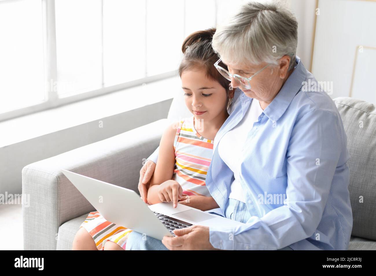 Little girl with her grandma using laptop at home Stock Photo - Alamy