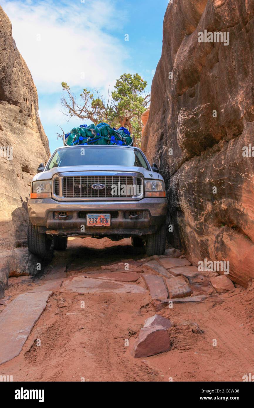 A 4-wheel drive SUV maneuvers through the very tight Squeeze Box on the Elephant Hill trail.  Canyonlands National Park, Utah.  Getting through the Sq Stock Photo