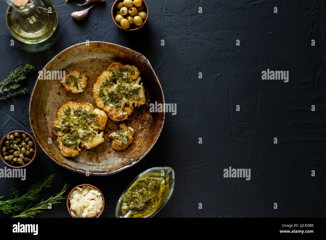 Cauliflower steak with spices lies in a frying pan. Olive oil