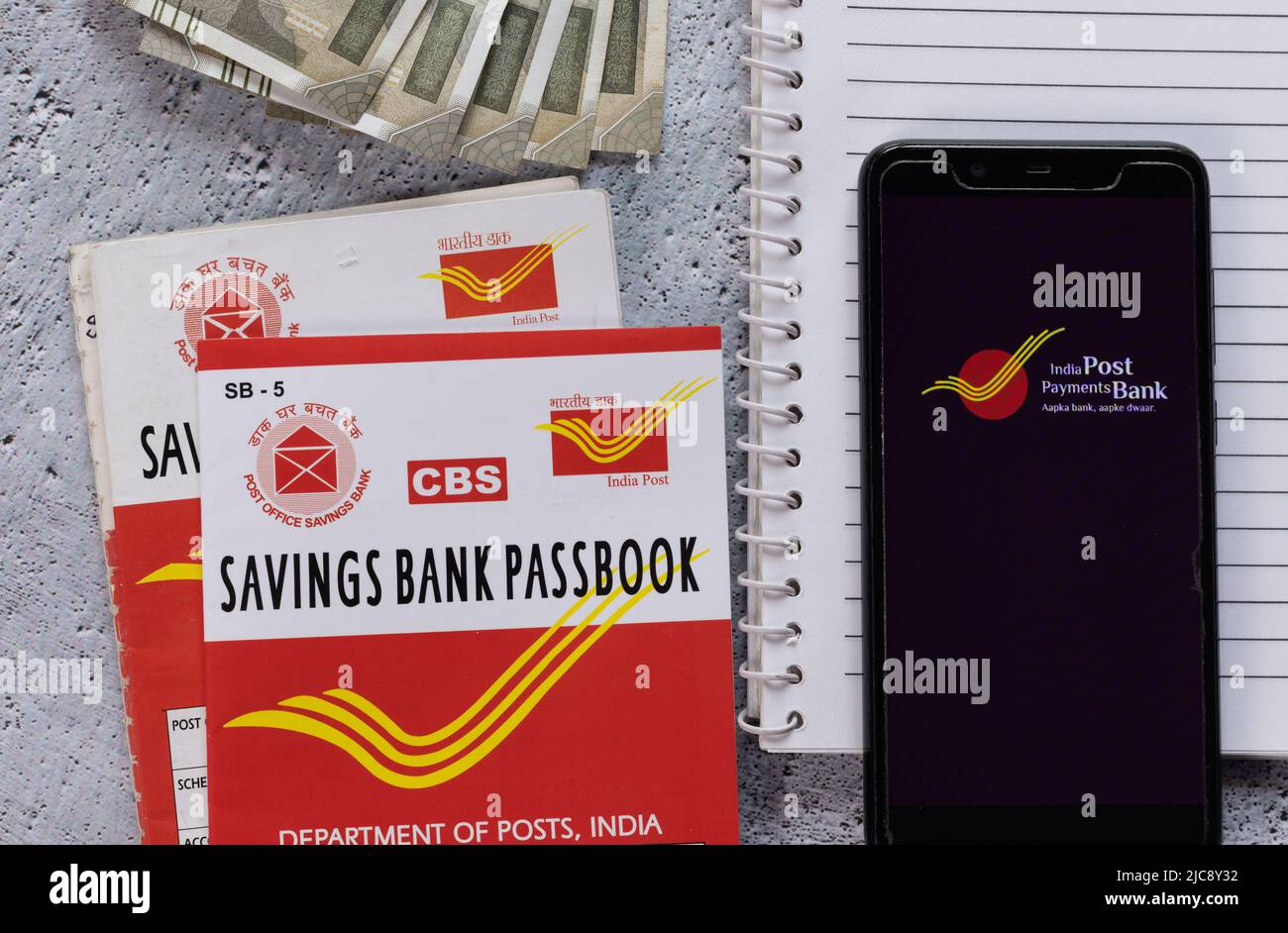 Birbhum, West Bengal, India - 25 April 2022: Top view of Indian post office savings books, currencies and smart phone with IPPB application Stock Photo
