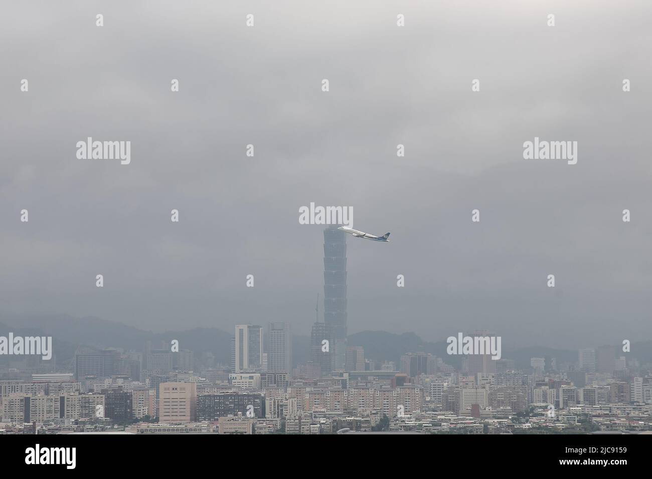 an airplane taking off from Taipei Songshan Airport (TSA) in a cloudy day in Taipei City, Taiwan Stock Photo
