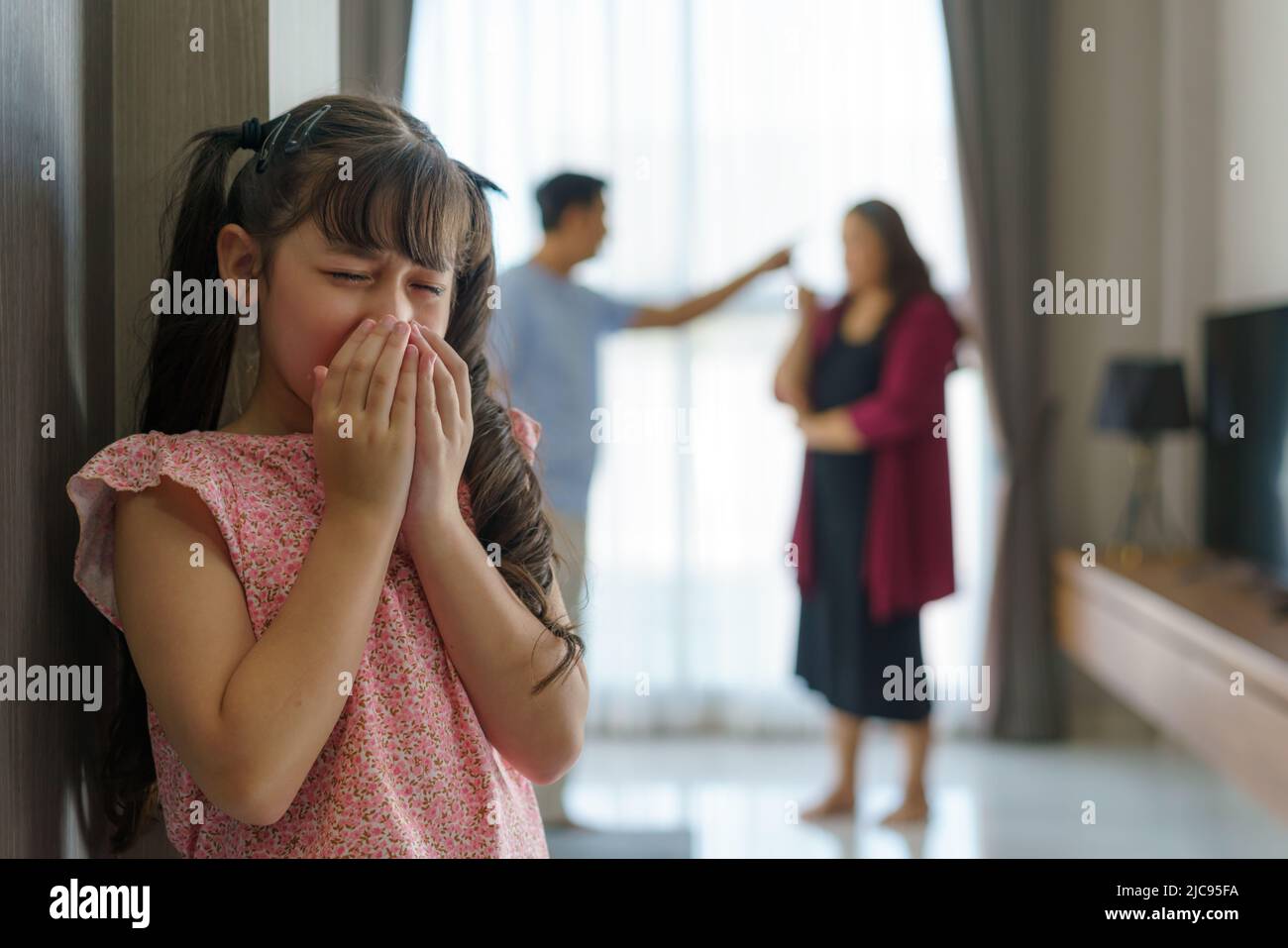 Family violence and family conflict concept, sad little girl with blur of mother fighting father with quarrel at home. Stock Photo