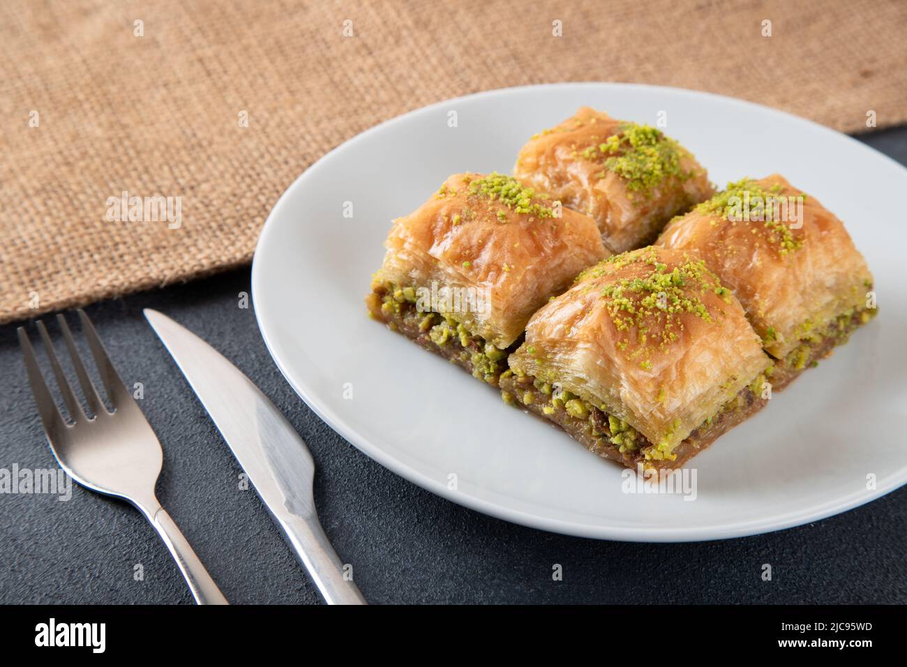 Traditional pistachio baklava in white plate.A plate baklava on dark background Stock Photo