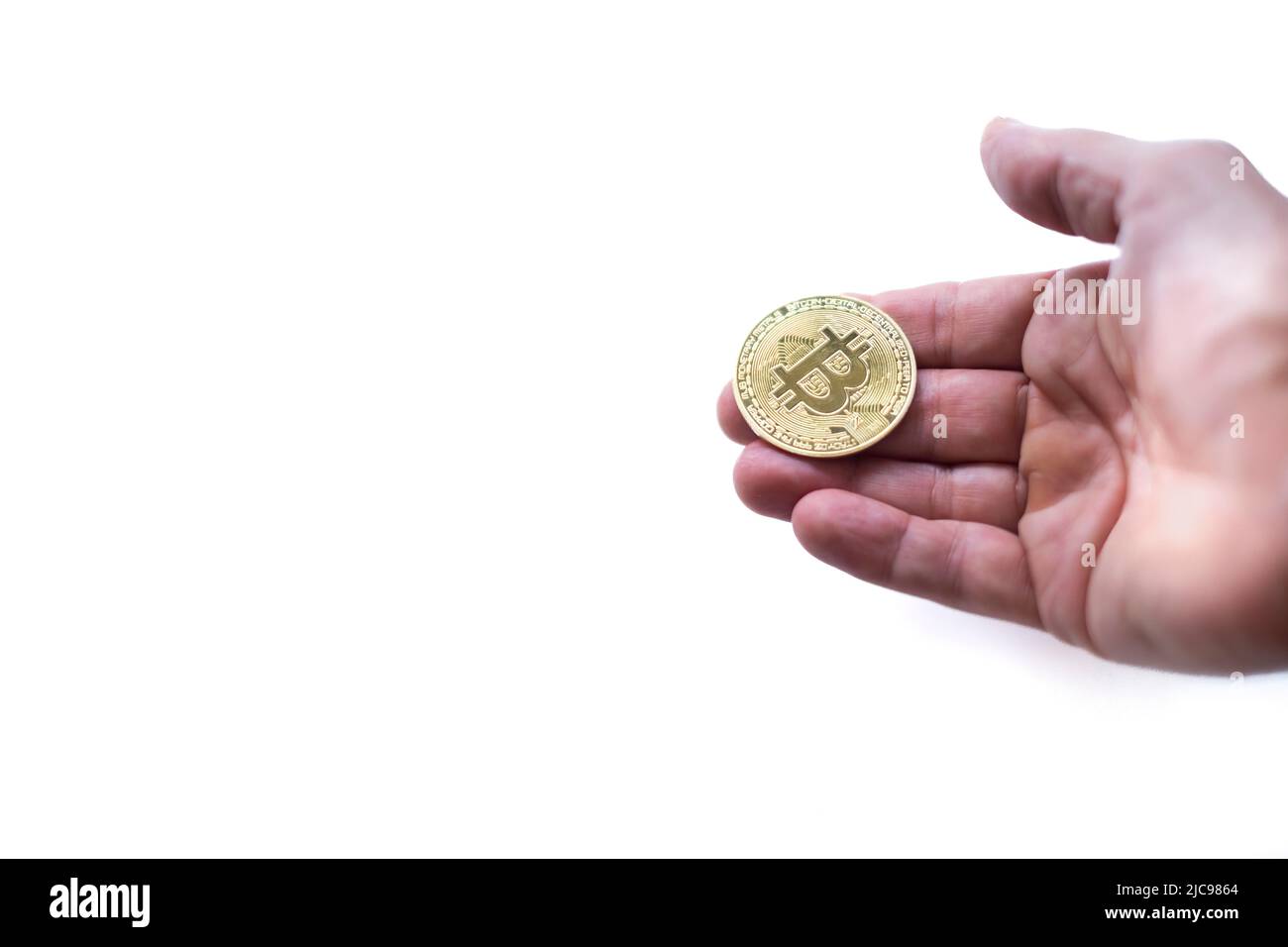 a hand holding a bit coin, as in a position to receive or accept a cryptocurrency as a payment form, white background, selective focus on the coin Stock Photo