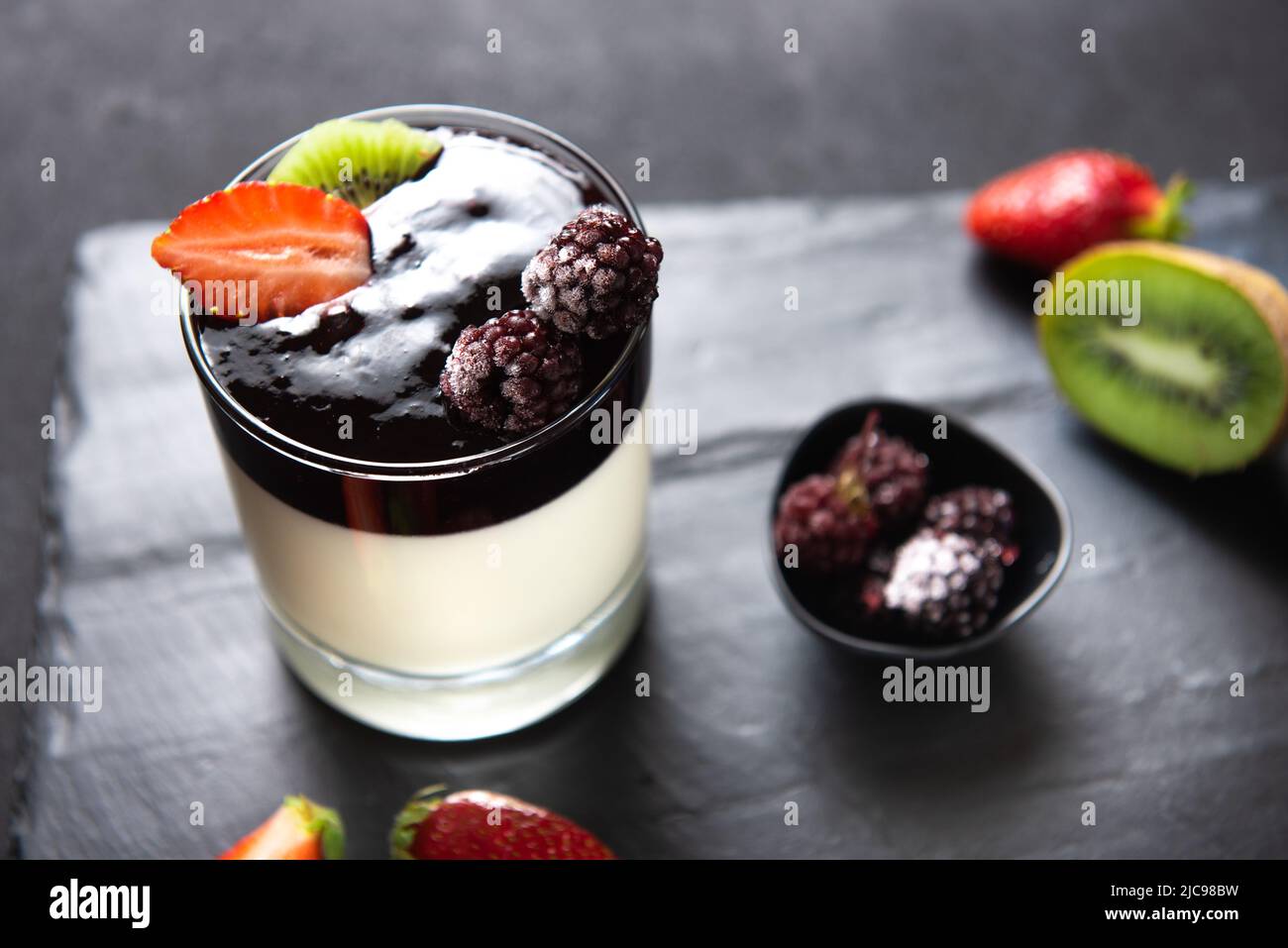 Italian dessert based on tops, zucur, gelatin and vanilla. Dessert panacotta on a serving board with strawberries and kiwi Stock Photo