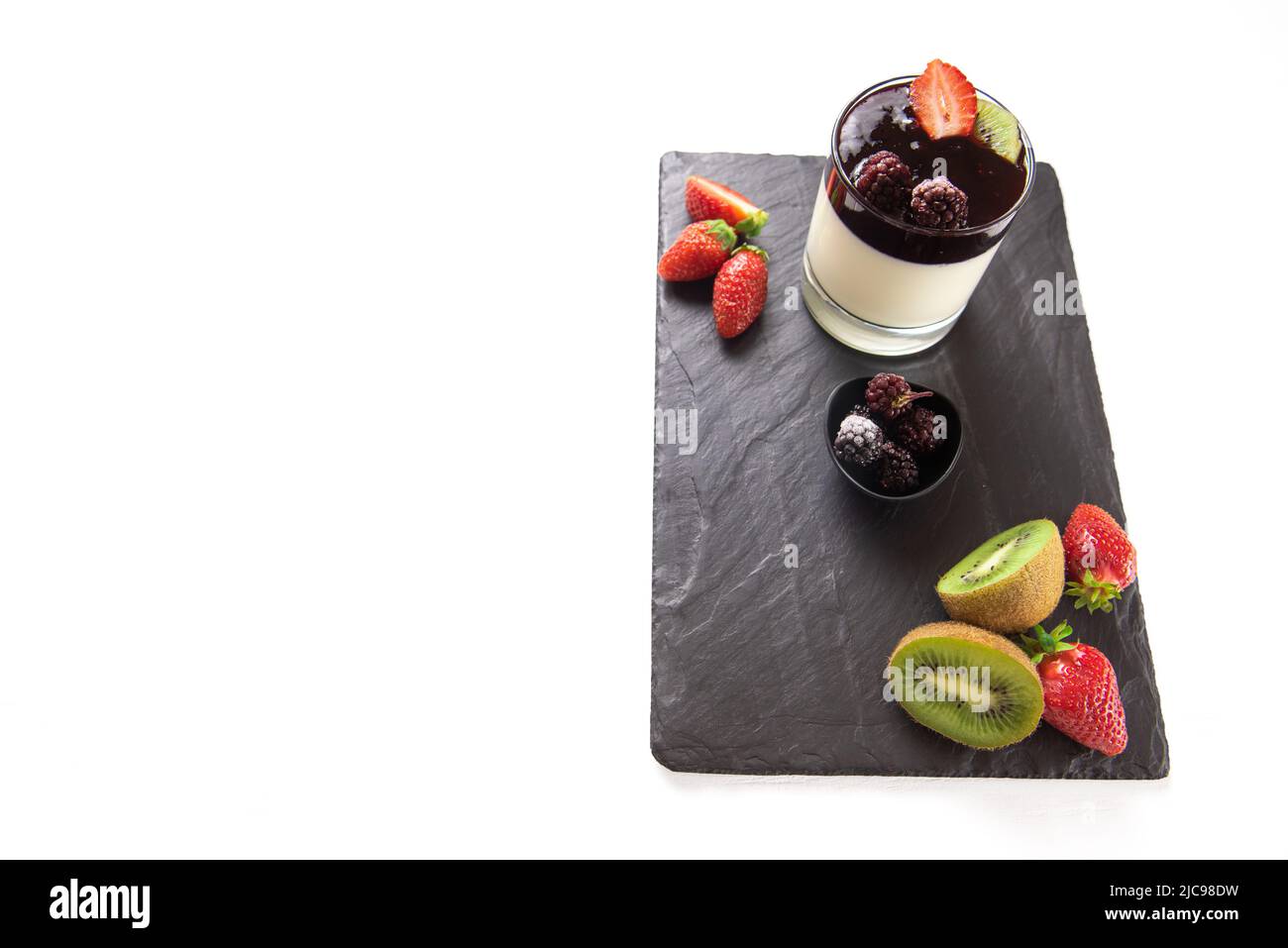 Panacotta on serving board with strawberries and kiwi. Empty space for text. Isolated Stock Photo