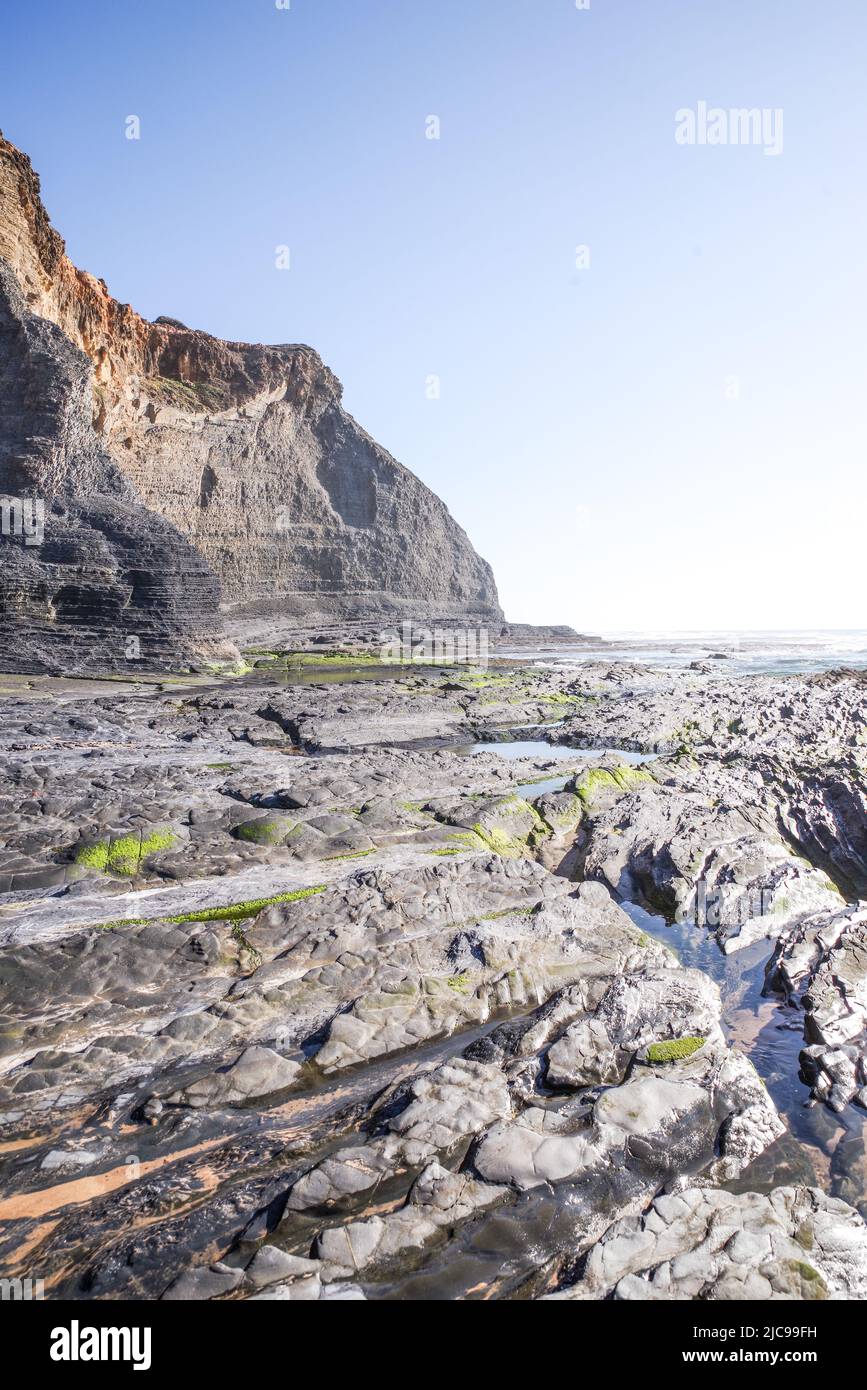 Dramatic volcanic cliffs framing the coast along Praia de Monte Clérigo in south west Algarve (Portugal) Stock Photo