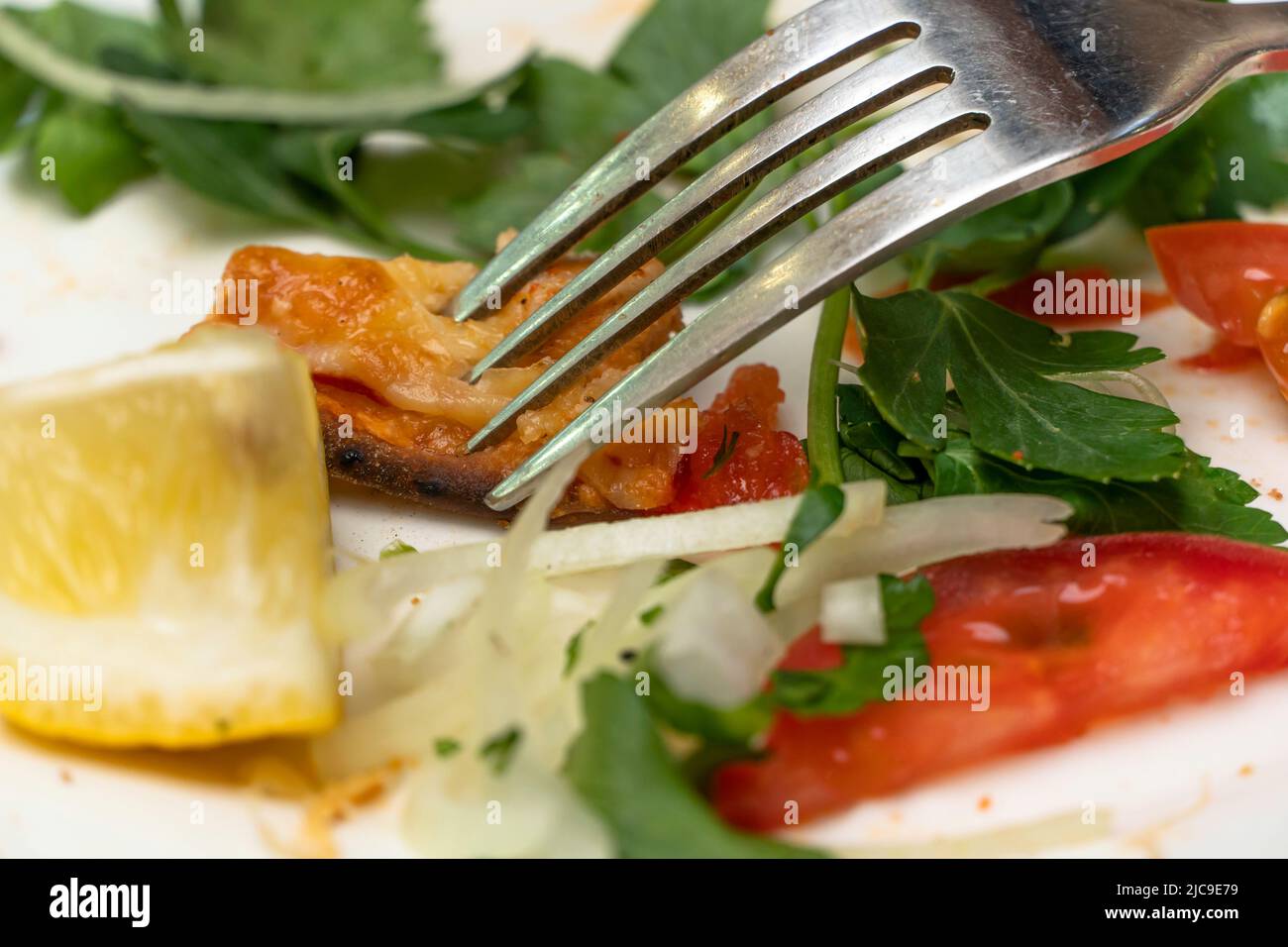 Leftovers on a plate close-up. Eat food with a knife and fork. Delicious lunch, vegetables, proper nutrition. Italian food. Useful menu. Enjoy dinner. Stock Photo