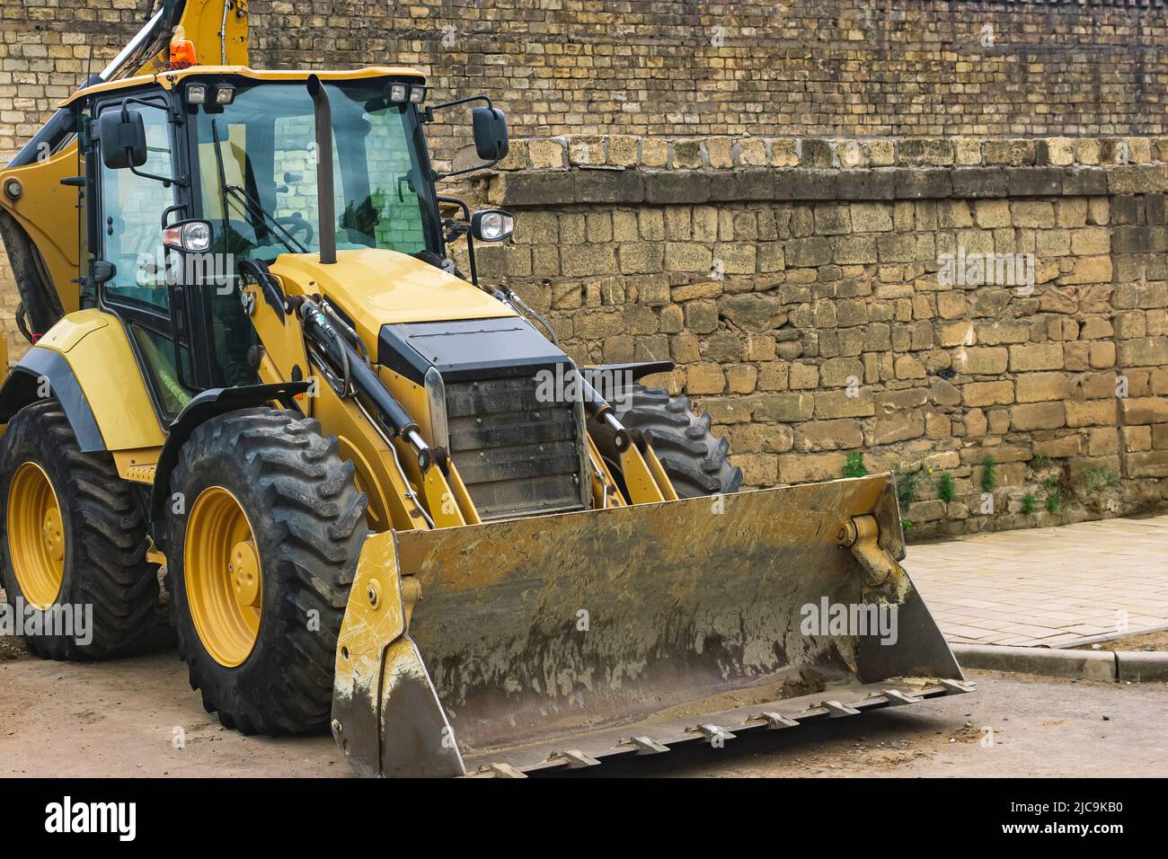 wheeled bucket loader next to a brick wall Stock Photo