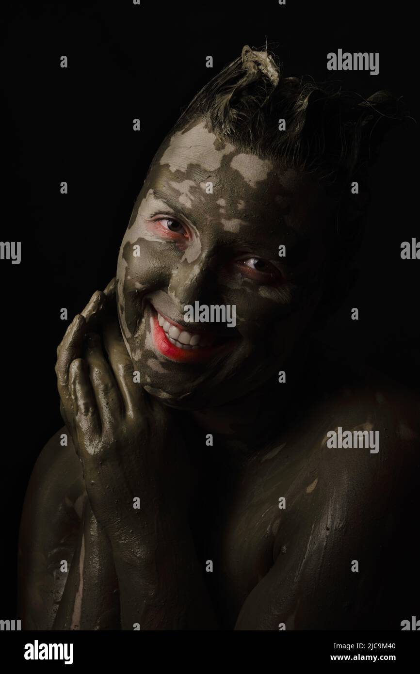 fun woman with black dirty smeared make up on black background Stock Photo