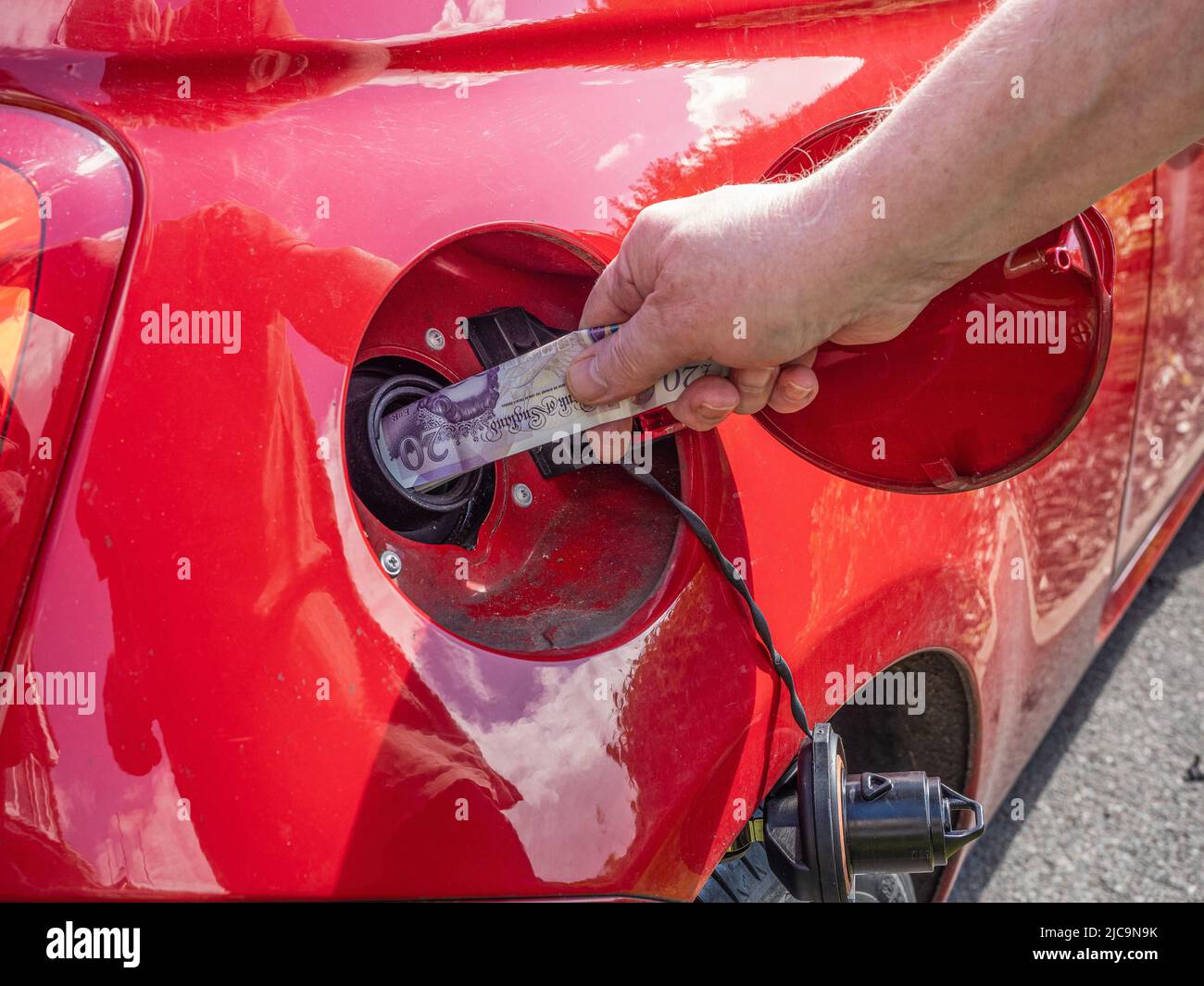 Petrol diesel fuel price rise crisis filling up the auto car vehicle at a gas service station in 2022 cash illustration in tank Stock Photo