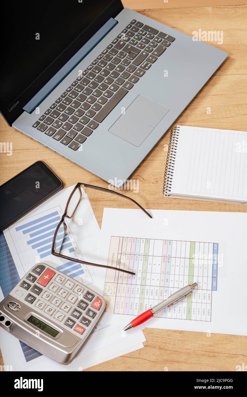 Work table at home with pen, papers, bills, charts, glasses, computer and calculator. Concept