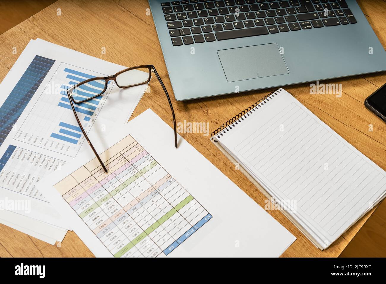 Work table at home with pen, papers, bills, charts, glasses, computer and calculator. Concept