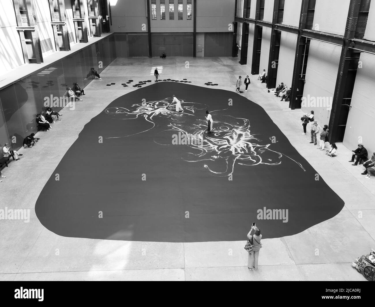 London, Greater London, England, June 08 2022: Monochrome. Interior of Tate Modern with a live exhibition watched by visitors. Stock Photo