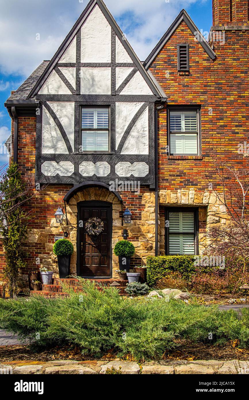 Closeup of beautiful entranceway of vintage brick and rock house with half timbered tudor gable with beautiful landscaping and door wreath Stock Photo