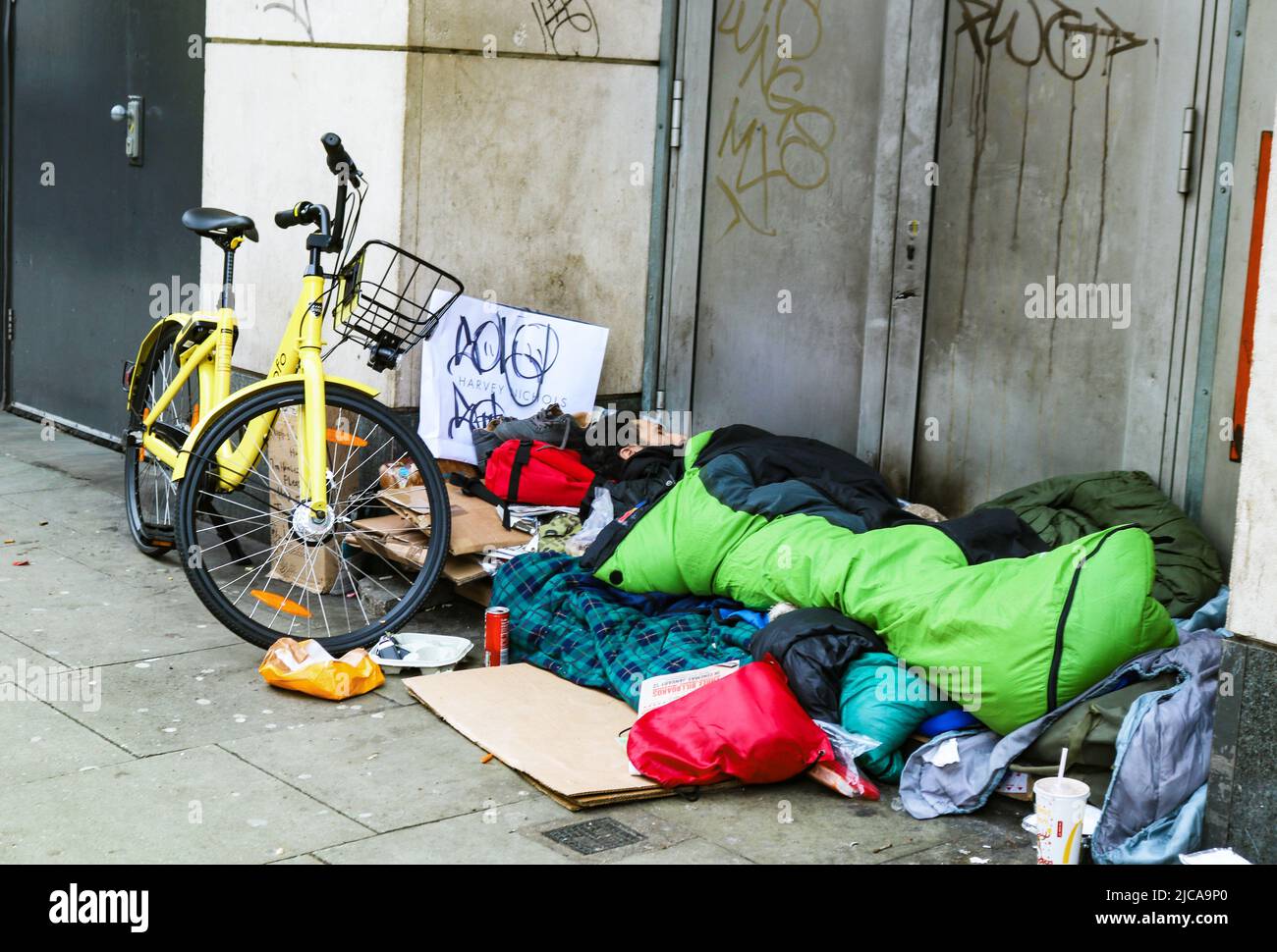 Homeless man with bicycle and sleeping bag asleep in doorway in South Kennsington London UK 1-10-2018 Stock Photo
