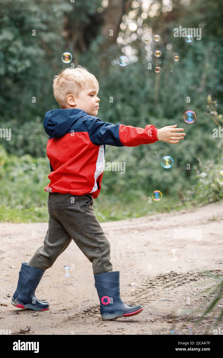 Little boy playing with his soap bubbles toy in the park. Child activity. Stock Photo
