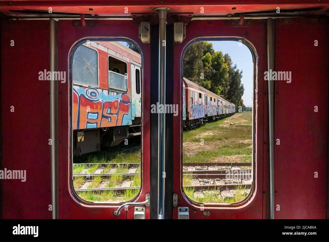Abandoned train through the window on the door of another old train in Durres, Albania Stock Photo
