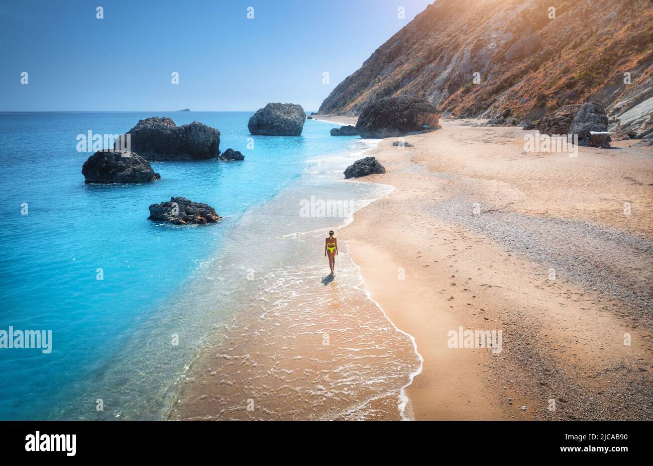 Aerial view of walking woman on the sandy beach, sea with waves Stock Photo