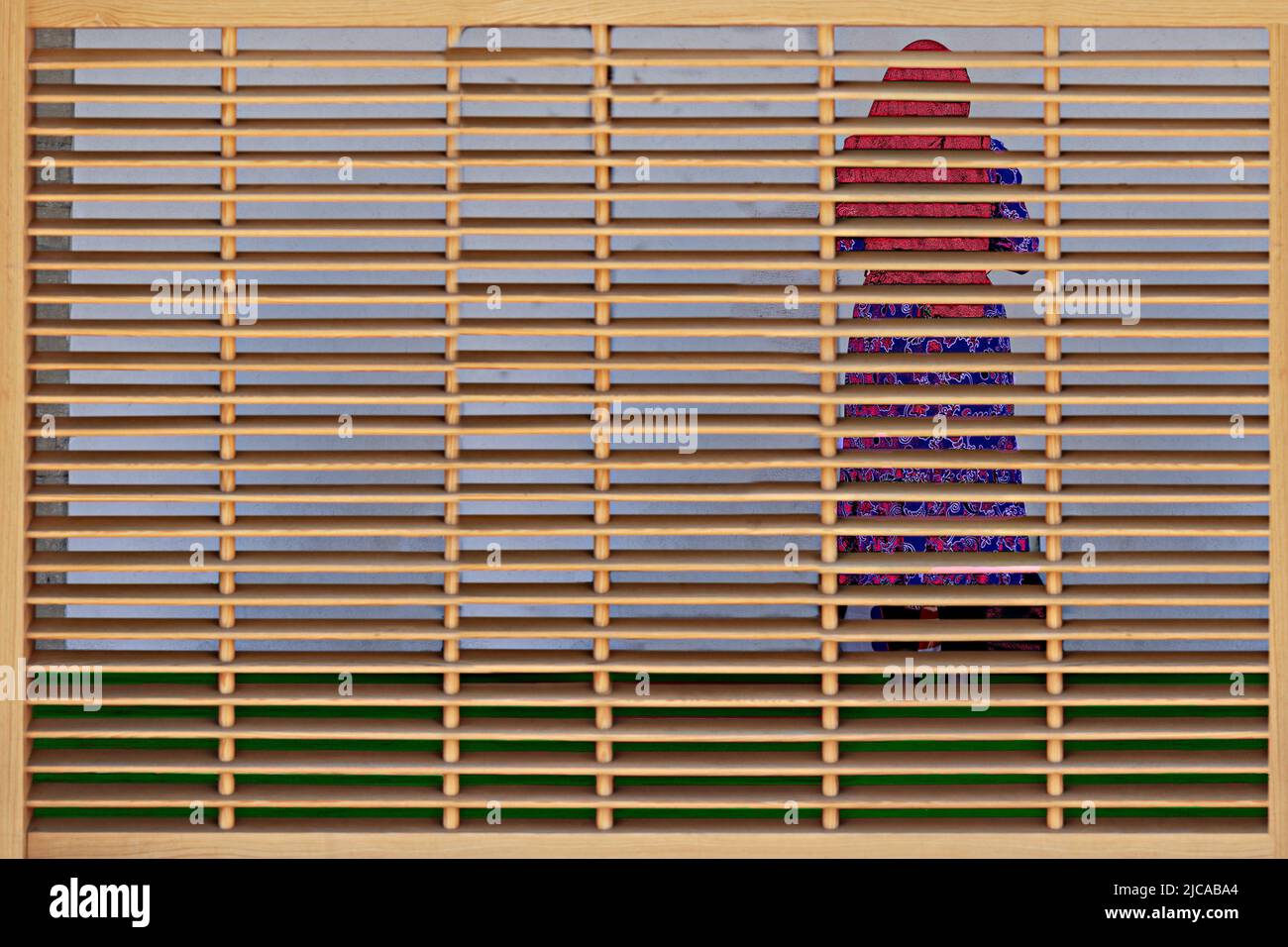 Muslim woman praying behind the screen in the women's section of the mosque. Stock Photo