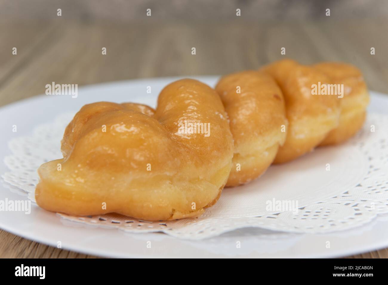 Tempting fresh from the oven glazed twist donut from the bakery served on a plate. Stock Photo