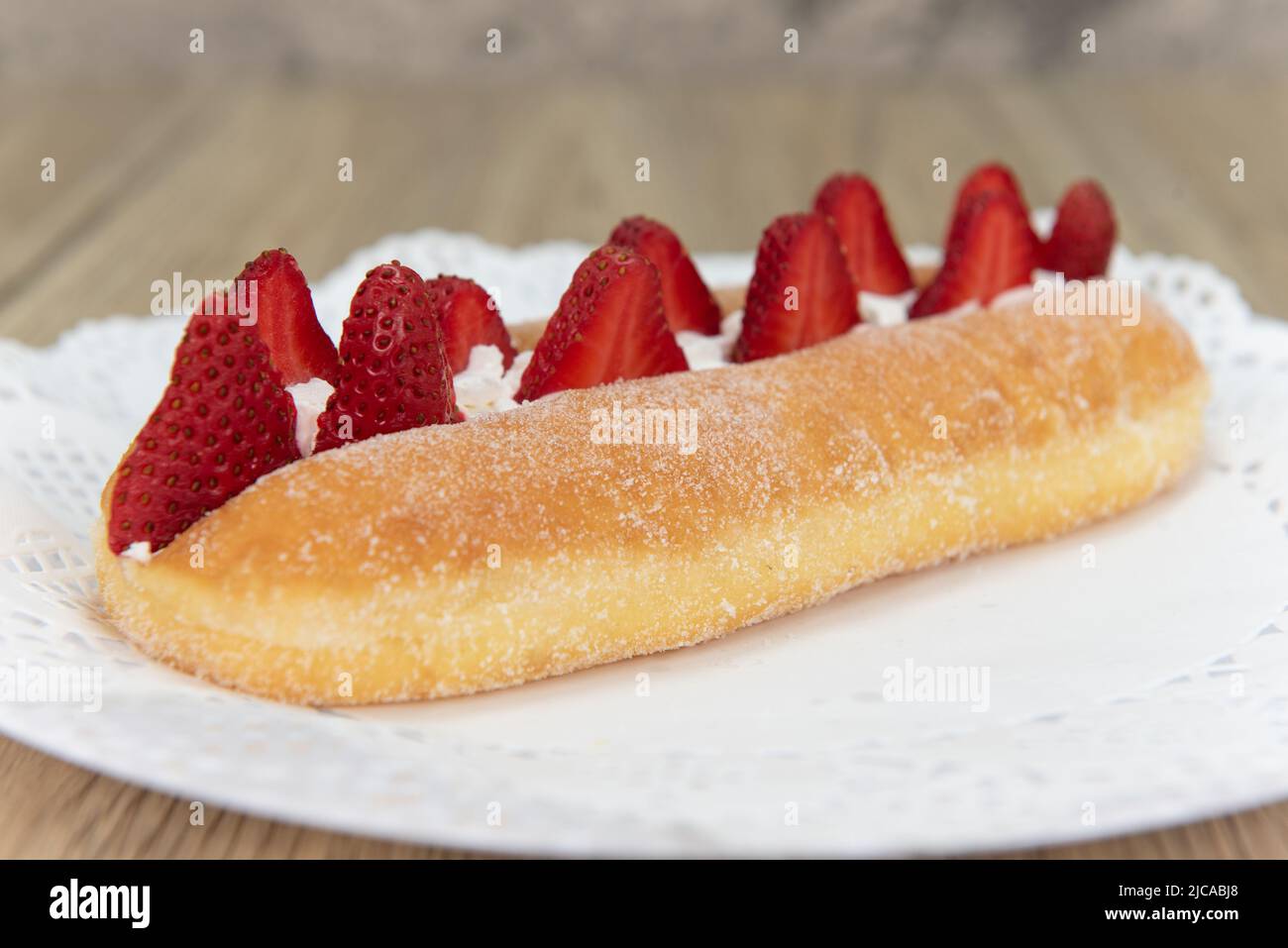 Tempting fresh from the oven fresh strawberry suguar donut from the bakery served on a plate. Stock Photo