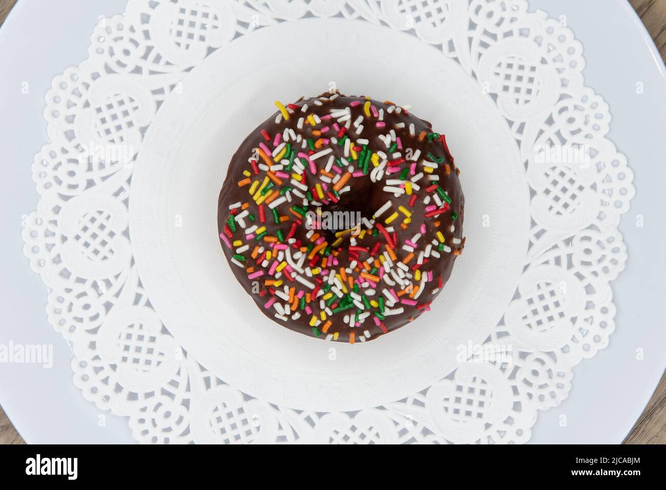 Overhead view of tempting fresh from the oven sprinked cake donut from the bakery served on a plate. Stock Photo