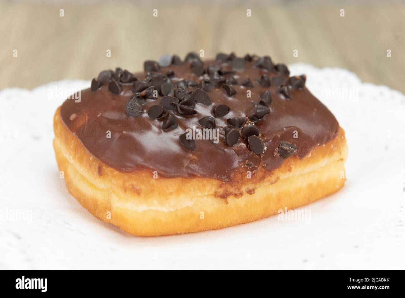 Tempting fresh from the oven chocolate chocolate chip donut from the bakery served on a plate. Stock Photo