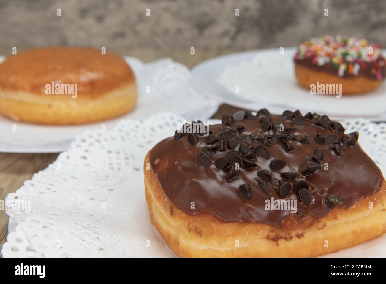 Tempting fresh from the oven buffet of donuts with the chocolate chip donut featured from the bakery served on a plate. Stock Photo