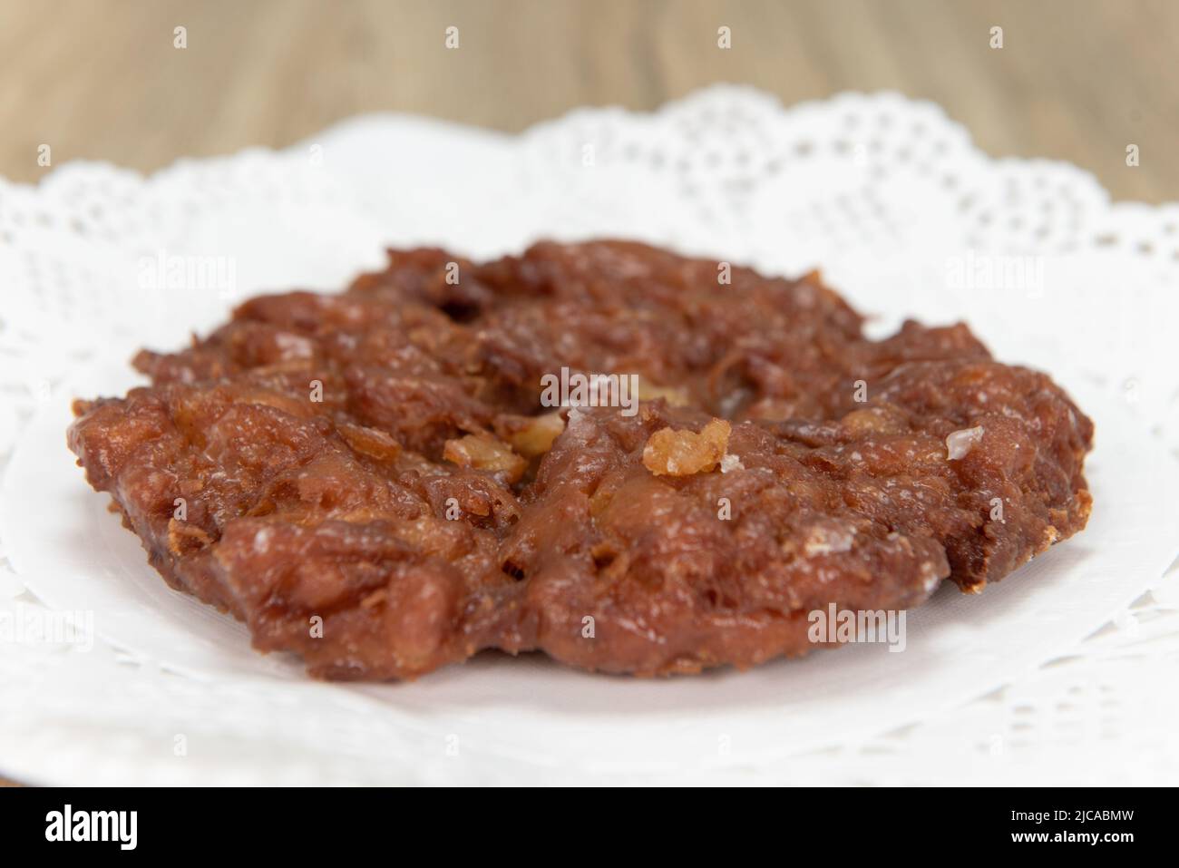 Tempting fresh from the oven apple fritter donut from the bakery served on a plate. Stock Photo