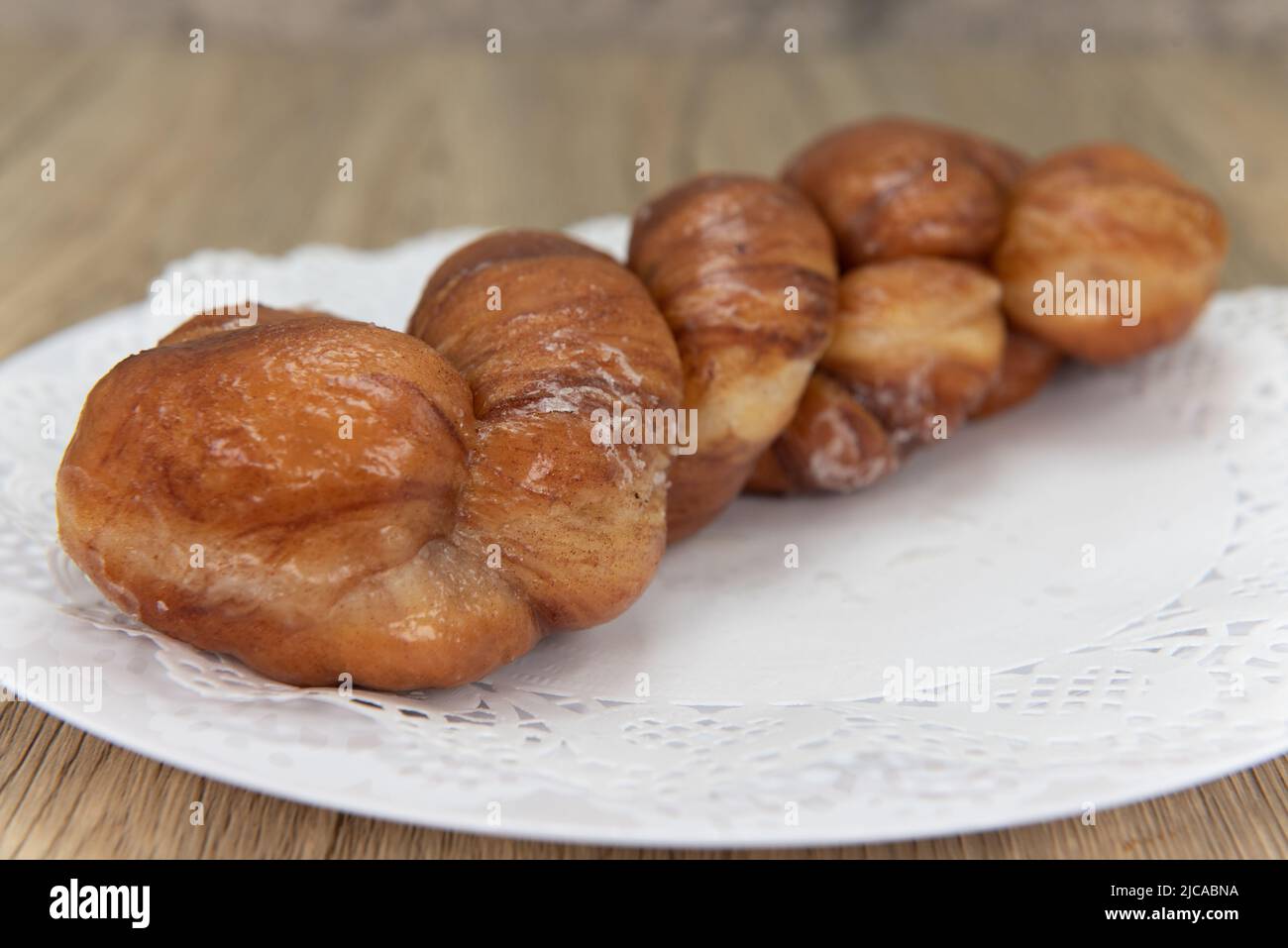 Tempting fresh from the oven cinnamon twist donut from the bakery served on a plate. Stock Photo