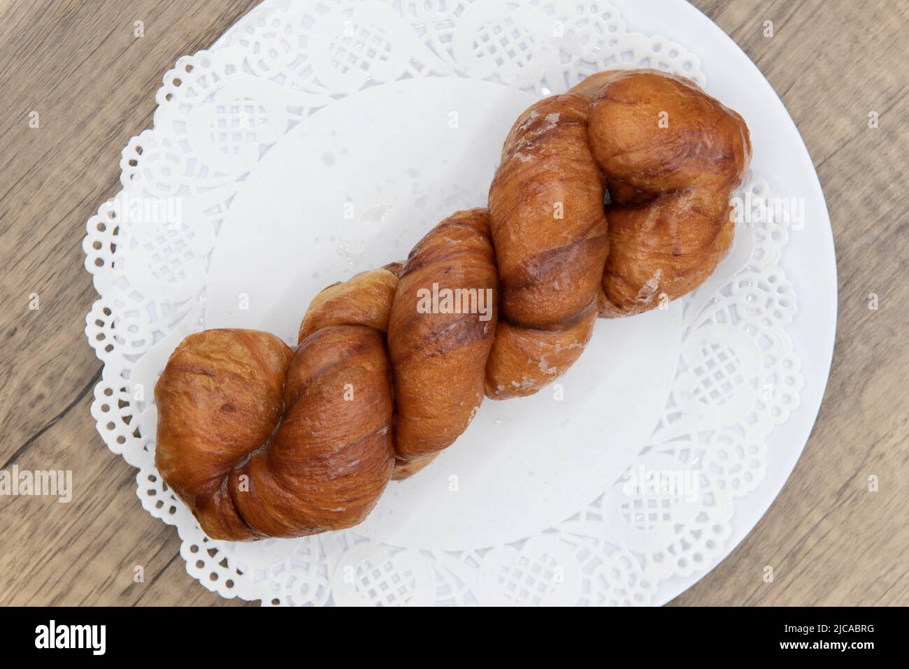Overhead view of tempting fresh from the oven cinnamon twist donut from the bakery served on a plate. Stock Photo