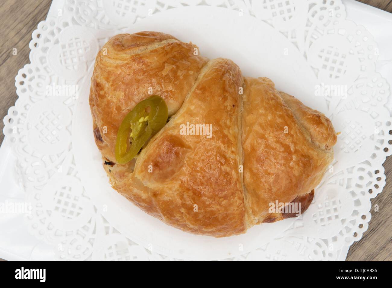 Overhead view of tempting fresh from the oven Ham and cheese jalapeno croissant sandwich from the bakery served on a plate. Stock Photo