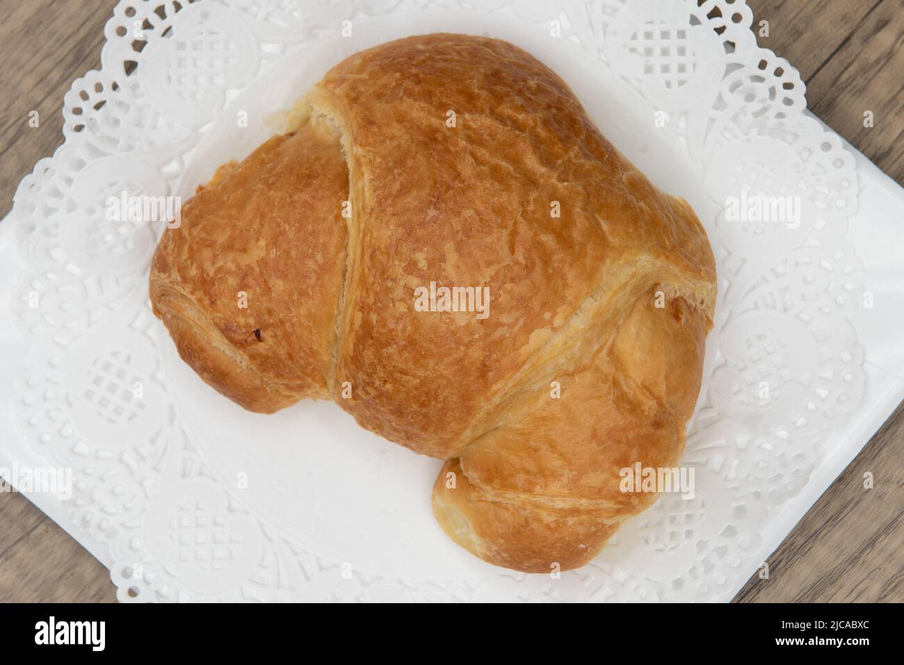 Overhead view of tempting fresh from the oven ham and cheese croissant from the bakery served on a plate. Stock Photo