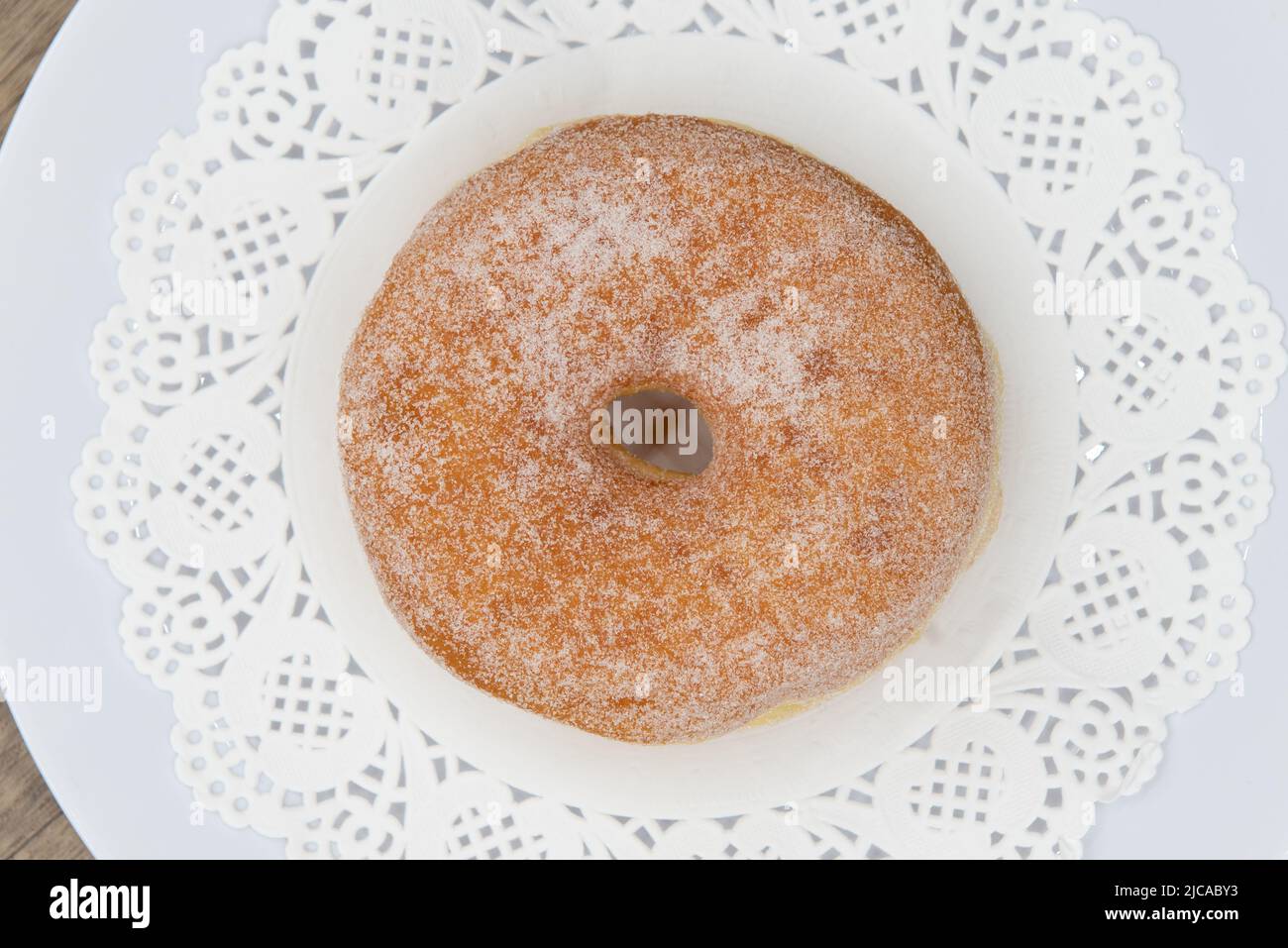 Overhead view of tempting fresh from the oven sugar glazed donut from the bakery served on a plate. Stock Photo