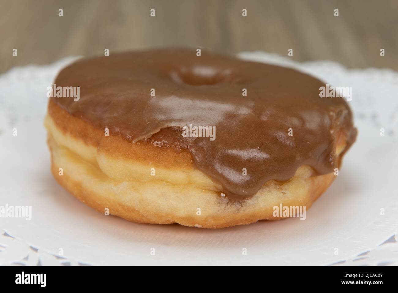 Tempting fresh from the oven maple donut from the bakery served on a plate. Stock Photo