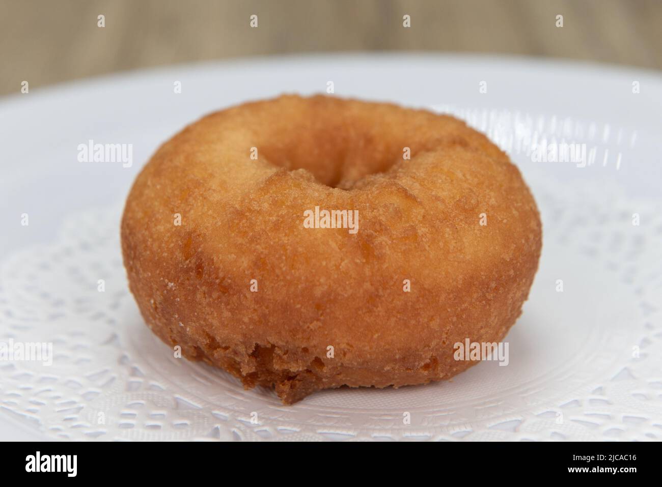 Tempting fresh from the oven plain donut from the bakery served on a plate. Stock Photo
