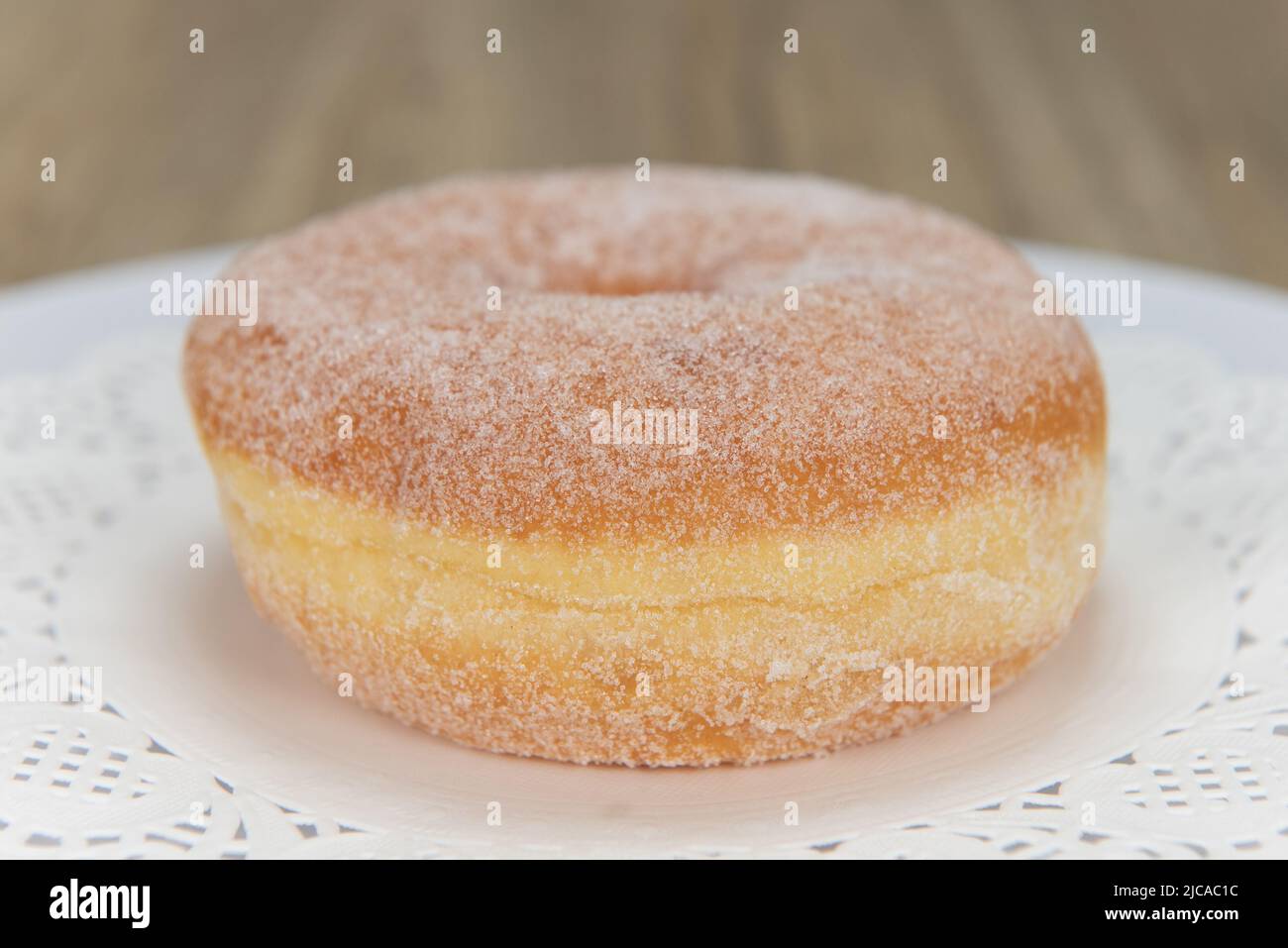 Tempting fresh from the oven sugar glazed donut from the bakery served on a plate. Stock Photo