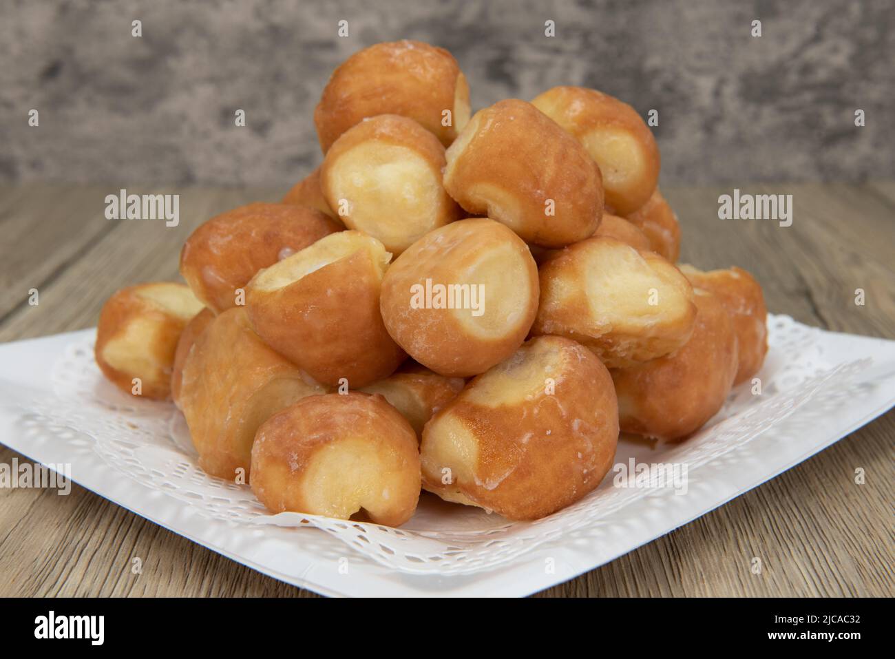 Tempting fresh from the oven glazed donut holes from the bakery stacked on a plate. Stock Photo