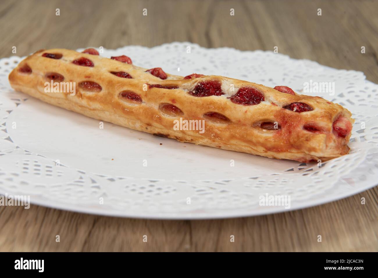 Tempting fresh from the oven strawberry strudel from the bakery served on a plate. Stock Photo