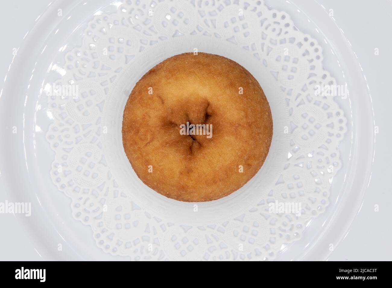 Overhead view of tempting fresh from the oven plain donut from the bakery served on a plate. Stock Photo