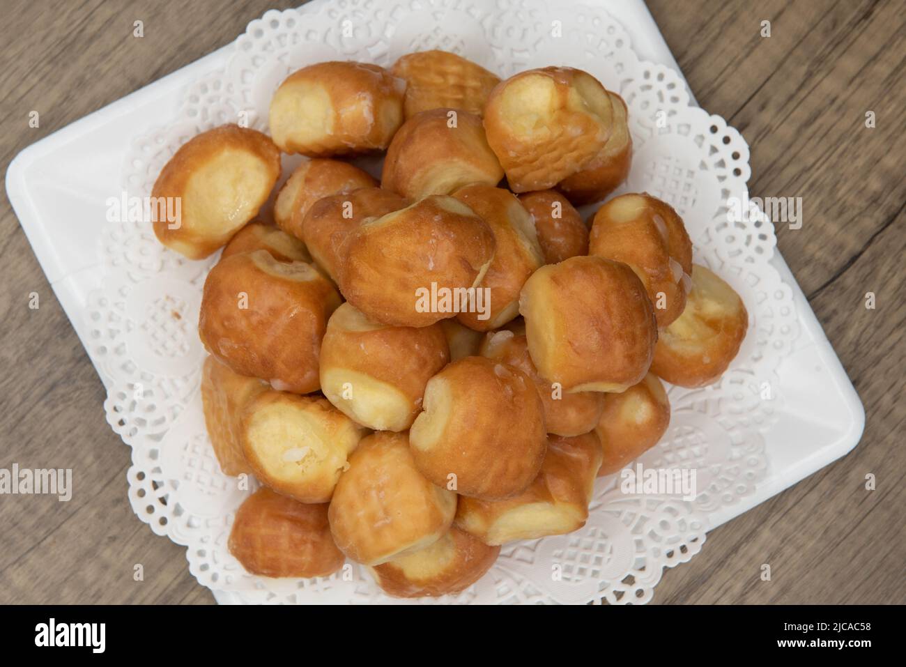 Overhead view of tempting fresh from the oven glazed donut holes from the bakery stacked on a plate. Stock Photo