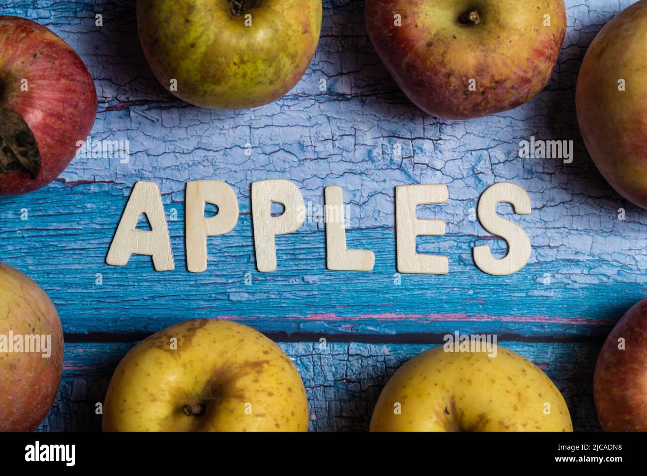 Many yellow and red apples fruit with apples word written on wooden